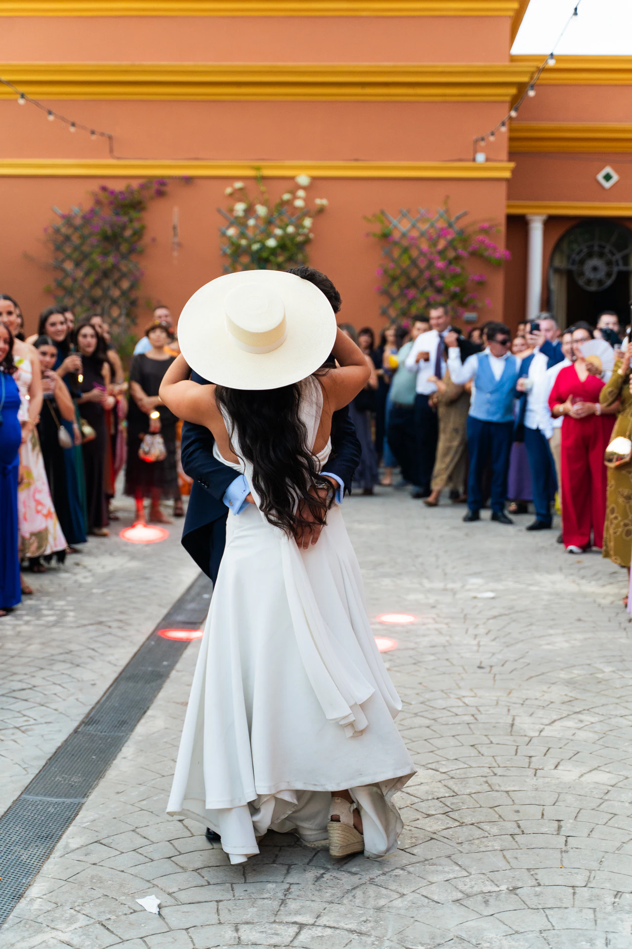 María baila con un sombrero de ala ancha entre los invitados en el patio